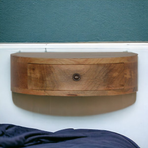 Raffinato comodino sospeso in legno massello di mango con finitura effetto rovere, profilo arrotondato e pratico cassetto.