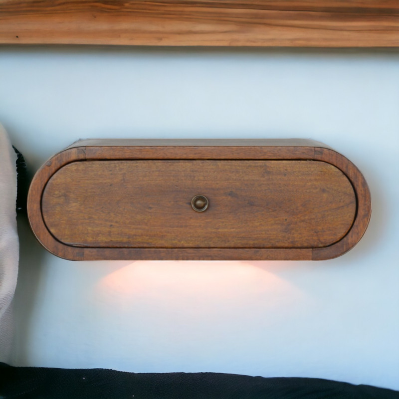 Raffinato comodino sospeso in legno massello di mango con finitura castagno, profilo rotondo, cassetto e pomello lucido.