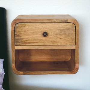 Elegante comodino da parete in legno massello di mango con finitura effetto rovere, cassetto, vano aperto e bordi curvi.