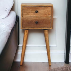 Comodino compatto in legno massello di mango effetto rovere, con due cassetti e quattro gambe di ispirazione scandinava.