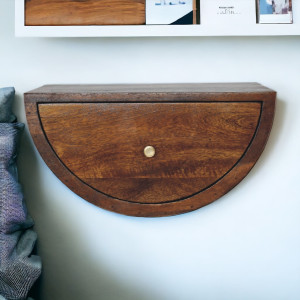 Comodino sospeso artigianale in mango massello con finitura castagno, forma a mezzaluna, cassetto e pomello in ottone.